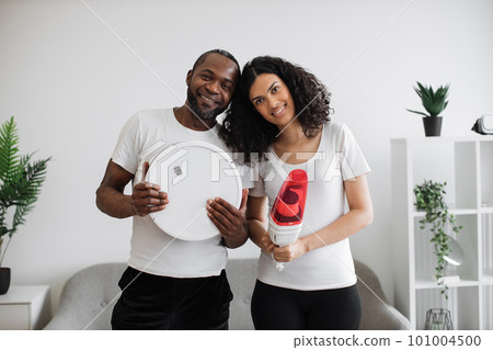 Multiethnic family holding two wireless vacuum cleaners 101004500