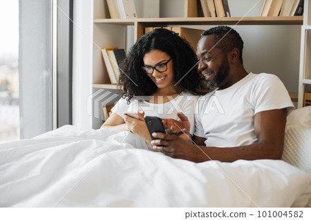 Multiracial family reading article on smartphones in bed 101004582