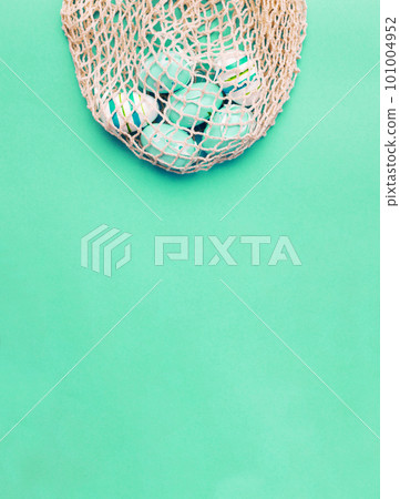 easter colorful painted eggs in the cotton string bag on green background. banner easter colorful painted eggs in the cotton string bag on green background. banner 101004952