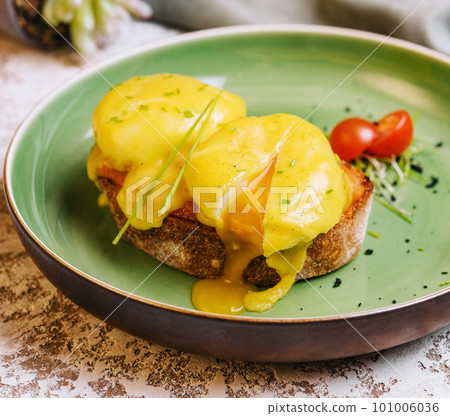Classic egg benedict on green plate Classic egg benedict on green plate 101006036