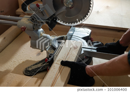 Master cuts the board with a circular saw in the workshop.  101006400