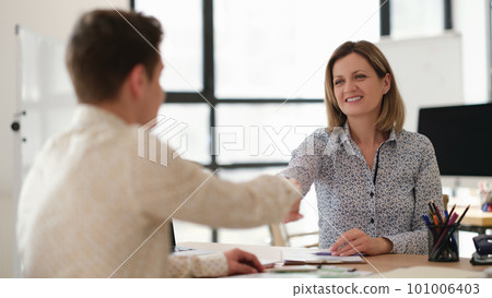 Business partners shaking hands at table in office when meeting 101006403