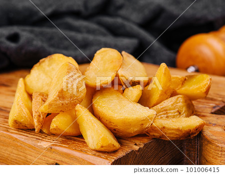 Roasted potato wedges on wooden board Roasted potato wedges on wooden board 101006415
