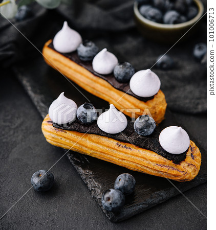 Beautiful and tasty eclairs on a slate board with petals 101006713
