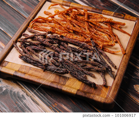 Beef and chiken jerky on wooden board 101006917