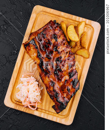 Pork loin ribs served on chopping board and potato wedges Pork loin ribs served on chopping board and potato wedges 101006967