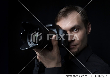 Close-up portrait of a professional photographer with a camera in the dark like a paparazzi 101007854