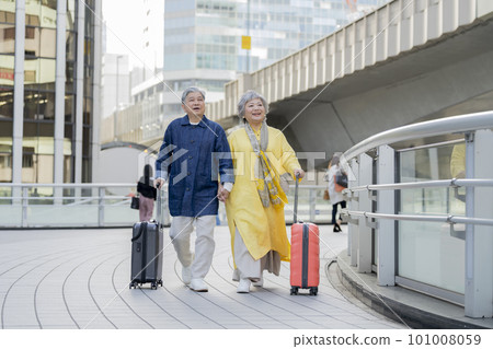 A couple in their 60s walking with a carry case travel image A couple in their 60s walking with a carry case travel image 101008059