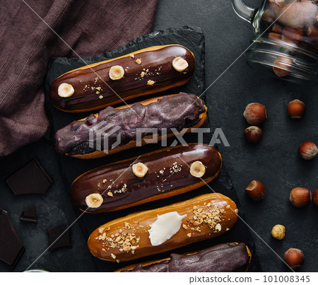 Sweet chocolate eclairs on black wooden board Sweet chocolate eclairs on black wooden board 101008345