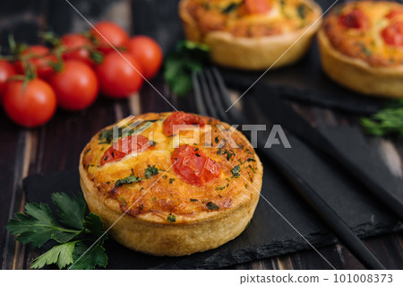 Cheddar cheese and spring onion omelette tarts served on wooden board 101008373