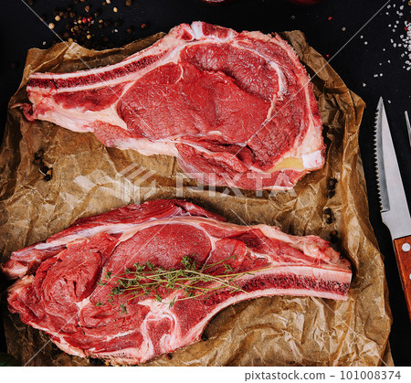 Two raw beef steaks on a baking paper 101008374