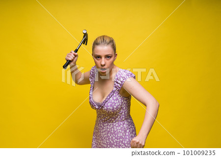 Beautiful seductive female holding hammer, isolated on yellow and red Beautiful seductive female holding hammer, isolated on yellow and red 101009235
