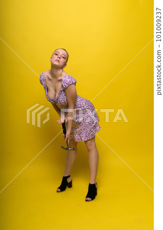 Beautiful seductive female holding hammer, isolated on yellow and red Beautiful seductive female holding hammer, isolated on yellow and red 101009237