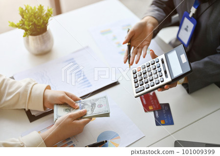 A professional female banker showing the profit margin on calculator to a customer. A professional female banker showing the profit margin on calculator to a customer. 101009399