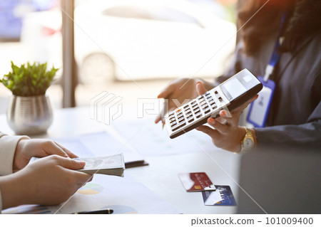 Female banker showing the profit margin on calculator to a customer. side view Female banker showing the profit margin on calculator to a customer. side view 101009400