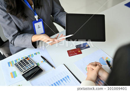 A female banker showing something on tablet screen while discussing with her client 101009401