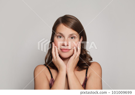 Pretty woman with natural fresh healthy skin touching her cheeks her hands on white Pretty woman with natural fresh healthy skin touching her cheeks her hands on white 101009699