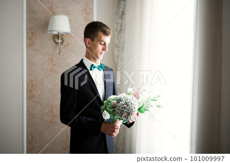 Grooms morning preparation. Handsome man getting dressed and preparing for the wedding 101009997