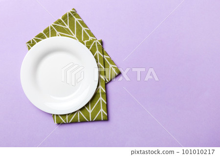 Top view on colored background empty round white plate on tablecloth for food. Empty dish on napkin with space for your design Top view on colored background empty round white plate on tablecloth for food. Empty dish on napkin with space for your design 101010217