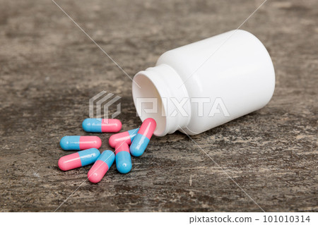 different drugs and health supplement pills poured from a medicine bottle health care and medical top view on colored background 101010314