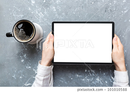 Close up image woman hands holding digital tablet with blank copy space screen for your text message or promotional content om table with cup of coffee. hands of a woman holding blank tablet device 101010588
