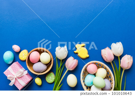 Easter frame with eggs, gift box and tulip on a colored background. The minimal concept. Top view Happy Easter composition. Card with a copy space of the place for the text Easter frame with eggs, gift box and tulip on a colored background. The minimal concept. Top view Happy Easter composition. Card with a copy space of the place for the text 101010643