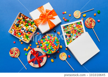 Set of different sweet candy in a paper box with a satin ribbon on a colored background. Holiday concept 101010645