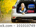 Adorable girl sitting ain a car trunk ready to go on vacations with her parents. Child looking forward for a road trip or travel. Autumn break at school. 101010749