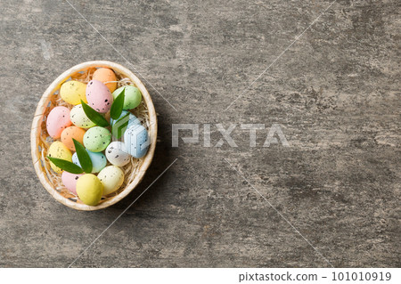 Colorful Easter eggs in wicker basket against colored background, closeup. top view with copy space Colorful Easter eggs in wicker basket against colored background, closeup. top view with copy space 101010919