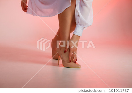 Woman's hand touches heel shoe on red background 101011787