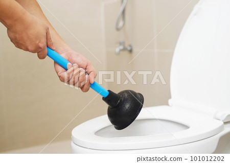 Serviceman repairing toilet with hand plunger. Clogged toilet. 101012202