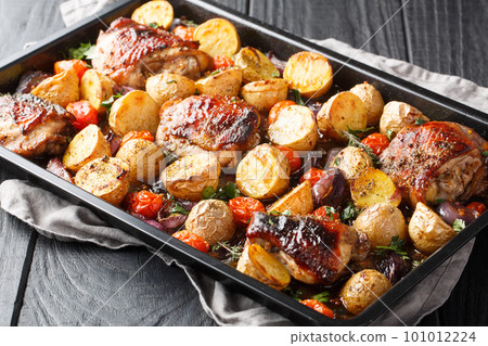 Delicious easy sheet pan Balsamic Chicken with Roasted Potatoes, Red Onion, Tomatoes and fresh herbs close-up. Horizontal Delicious easy sheet pan Balsamic Chicken with Roasted Potatoes, Red Onion, Tomatoes and fresh herbs close-up. Horizontal 101012224