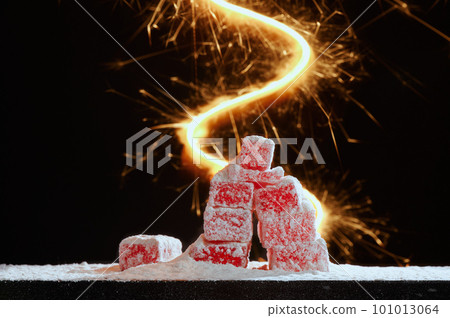 Strawberry red marmalade jelly candy's covered with powder sugar on black background with bright flash . Photo with copy space. The concept of Christmas sweets. 101013064