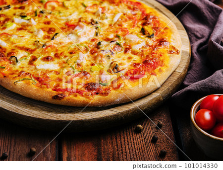 Delicious pizza with seafood on wooden stand 101014330