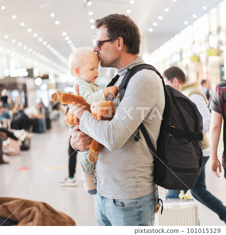 Father traveling with child, holding his infant baby boy at airport terminal waiting to board a plane. Travel with kids concept 101015329