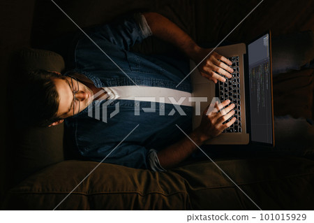 Programmer laying on sofa and working at his laptop 101015929