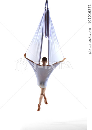 Professional male aerial gymnast training with transparent silk fabric against white studio background. Young sportsman. Back view 101016271