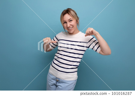 optimistic photo of a positive cheerful blond girl in a striped sweater on a blue background with optimistic photo of a positive cheerful blond girl in a striped sweater on a blue background with 101016287