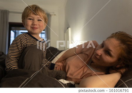 Little smiling blonde boy on the bed with his mother 101016791