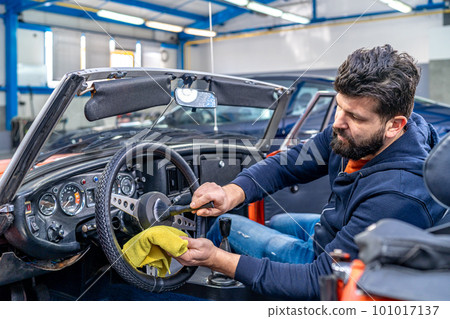 cleaning the interior of the old car with a brush and rag 101017137