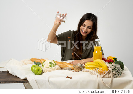 Happy woman in green t-shirt with a mesh eco bag with healthy vegan vegetables, fruits, bread and snacks. Healthy eating vegetarian concept. Happy woman in green t-shirt with a mesh eco bag with healthy vegan vegetables, fruits, bread and snacks. Healthy eating vegetarian concept. 101017196