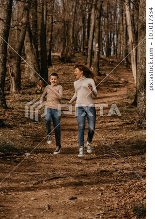Happy Mother and Son Running on Path in Forest 101017334