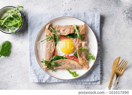 homemade buckwheat crepe galette with egg, ham and spinach on gray background. Traditional French dish. top view 101017890