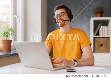 Happy guy with headphones using laptop at home 101017949