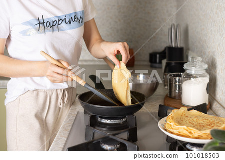woman turns over hot thin pancakes with spatula woman turns over hot thin pancakes with spatula 101018503