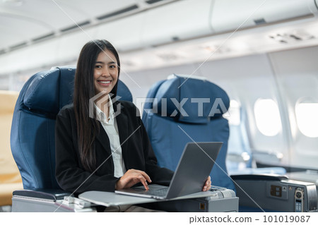 Female passenger sitting on plane while working on laptop computer with simulated space using on board wireless connection 101019087