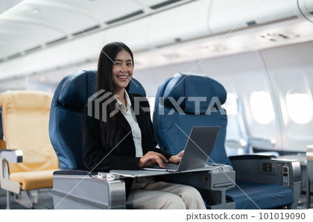 Female passenger sitting on plane while working on laptop computer with simulated space using on board wireless connection 101019090
