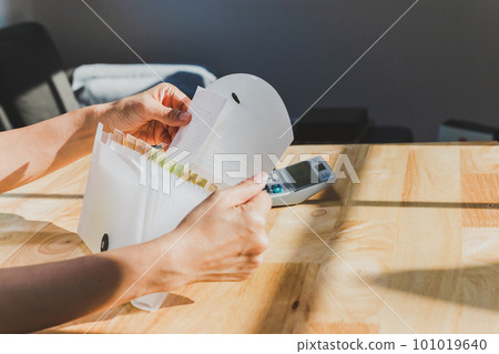 Woman hands organizing folder on a desk at home. Woman hands organizing folder on a desk at home. 101019640