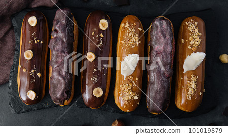 Sweet chocolate eclairs on black wooden board Sweet chocolate eclairs on black wooden board 101019879