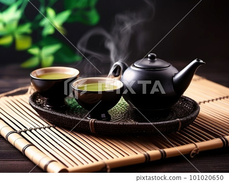 Asian tea set. Japanese teapot and cups on bamboo mat. Hot tea in pot and teacups Asian tea set. Japanese teapot and cups on bamboo mat. Hot tea in pot and teacups 101020650